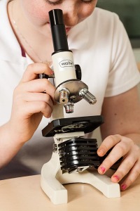 Science student looking at samples through microscope
